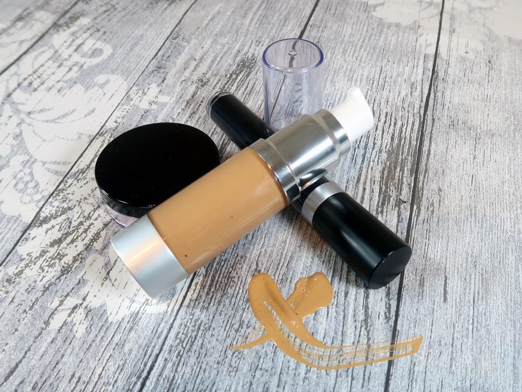 Liquid foundation sitting with a blush sifter and mascara tube