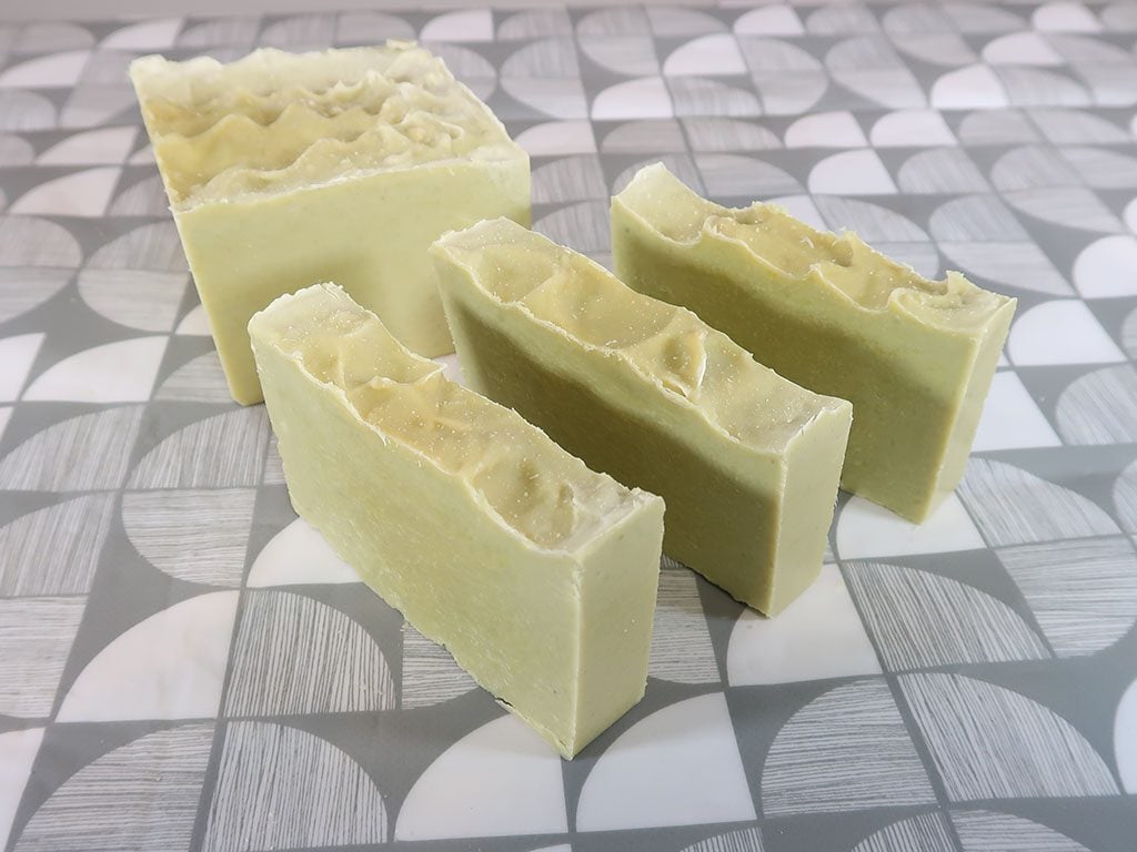 3 bars of organic soap sit next to a block of the same soap