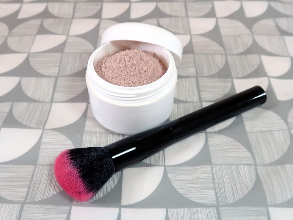 A pot of powdered foundation and a large application brush