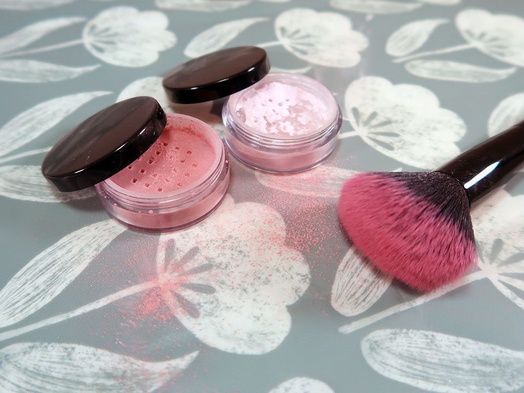 Two powdered blushes sit next to a blusher brush